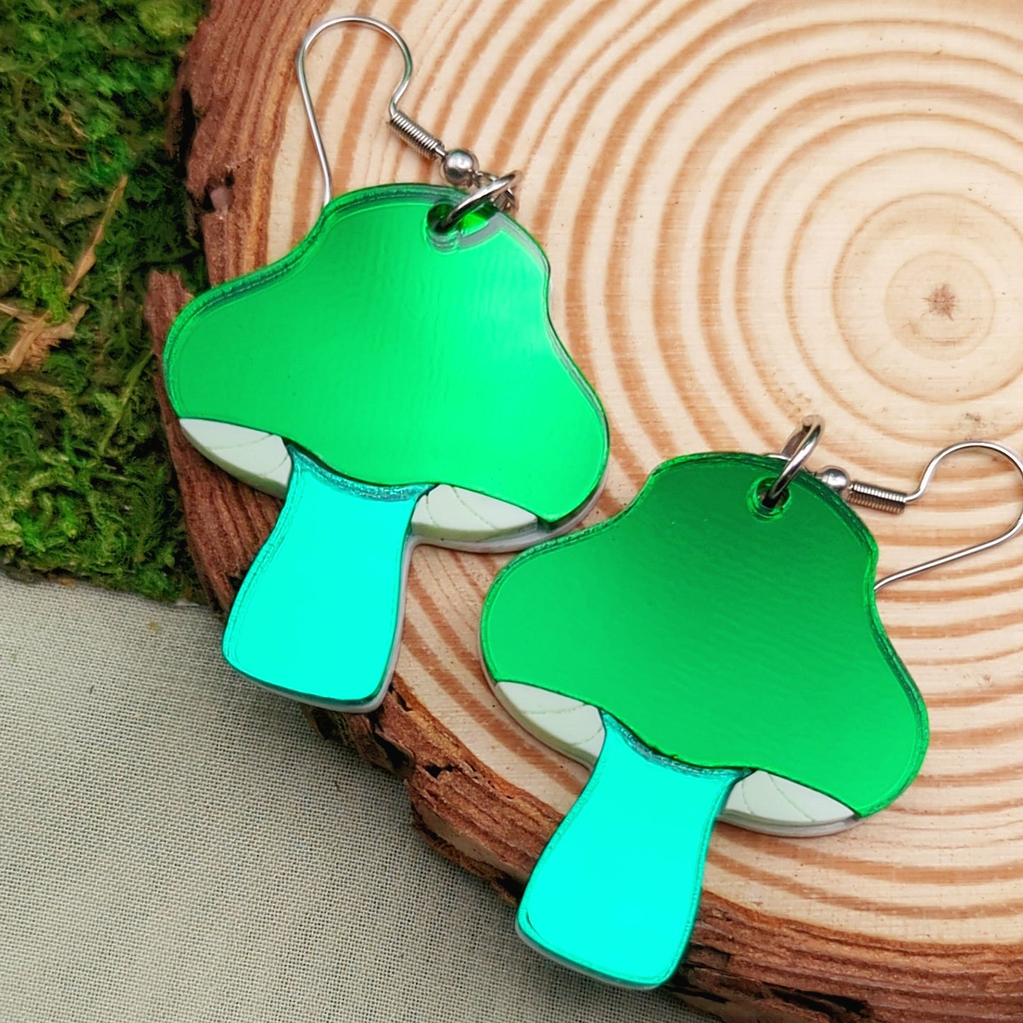 Inky cap mushroom earrings made with beige and dark gray acrylics on stainless steel fishhooks on a wood slice