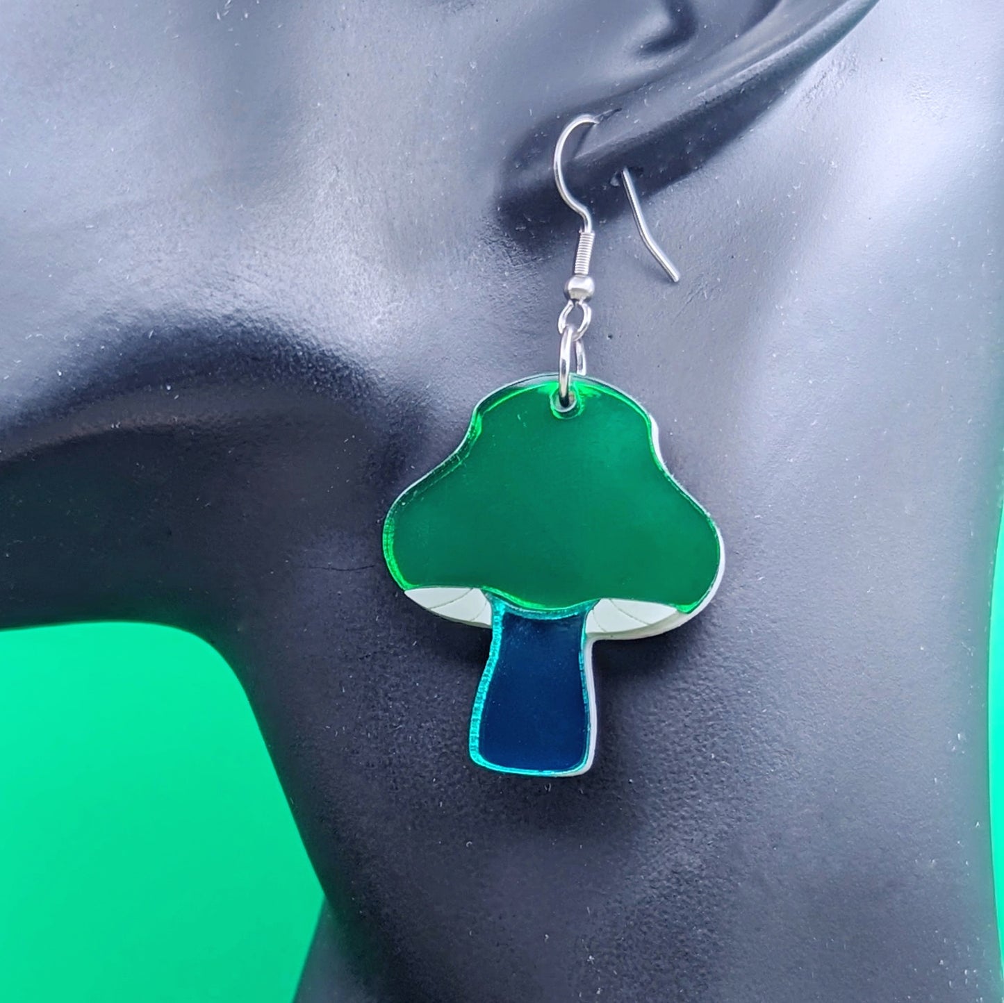 Inky cap mushroom earrings made with beige and dark gray acrylics on stainless steel fishhooks on a model ear
