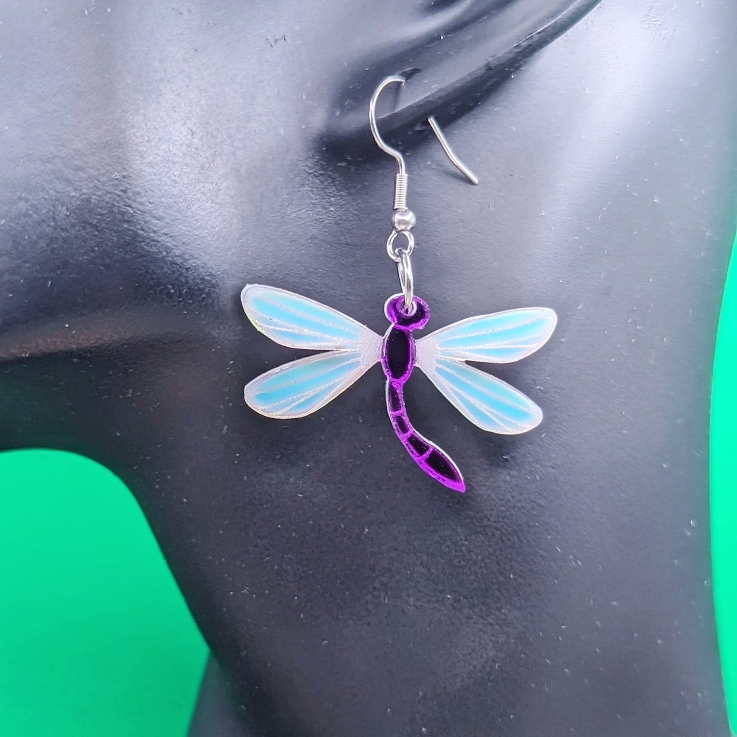 Purple dragonfly dangle earrings with matte iridescent engraved wings on a model ear.