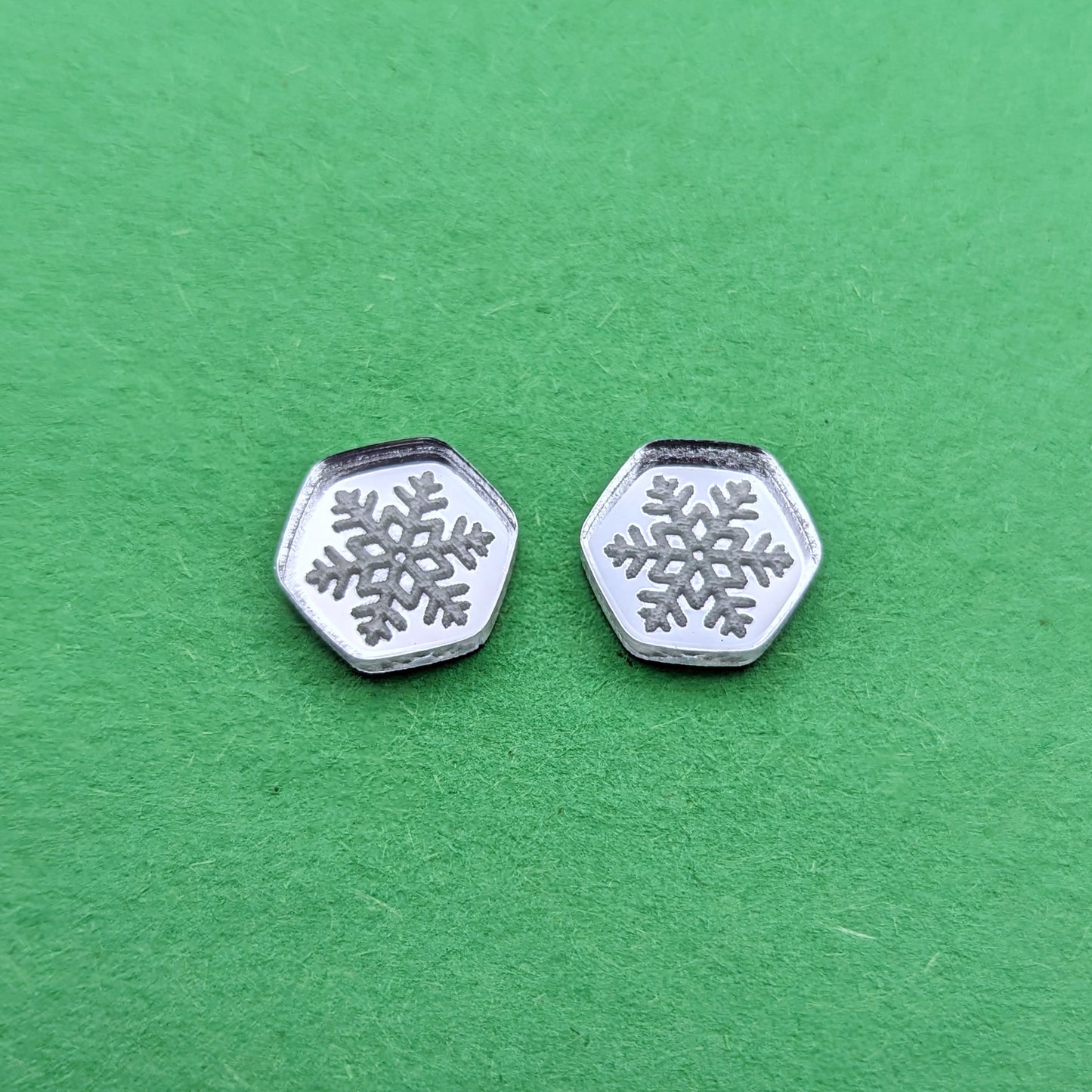 Silver acrylic hexagon stud earrings with engraved snowflakes.