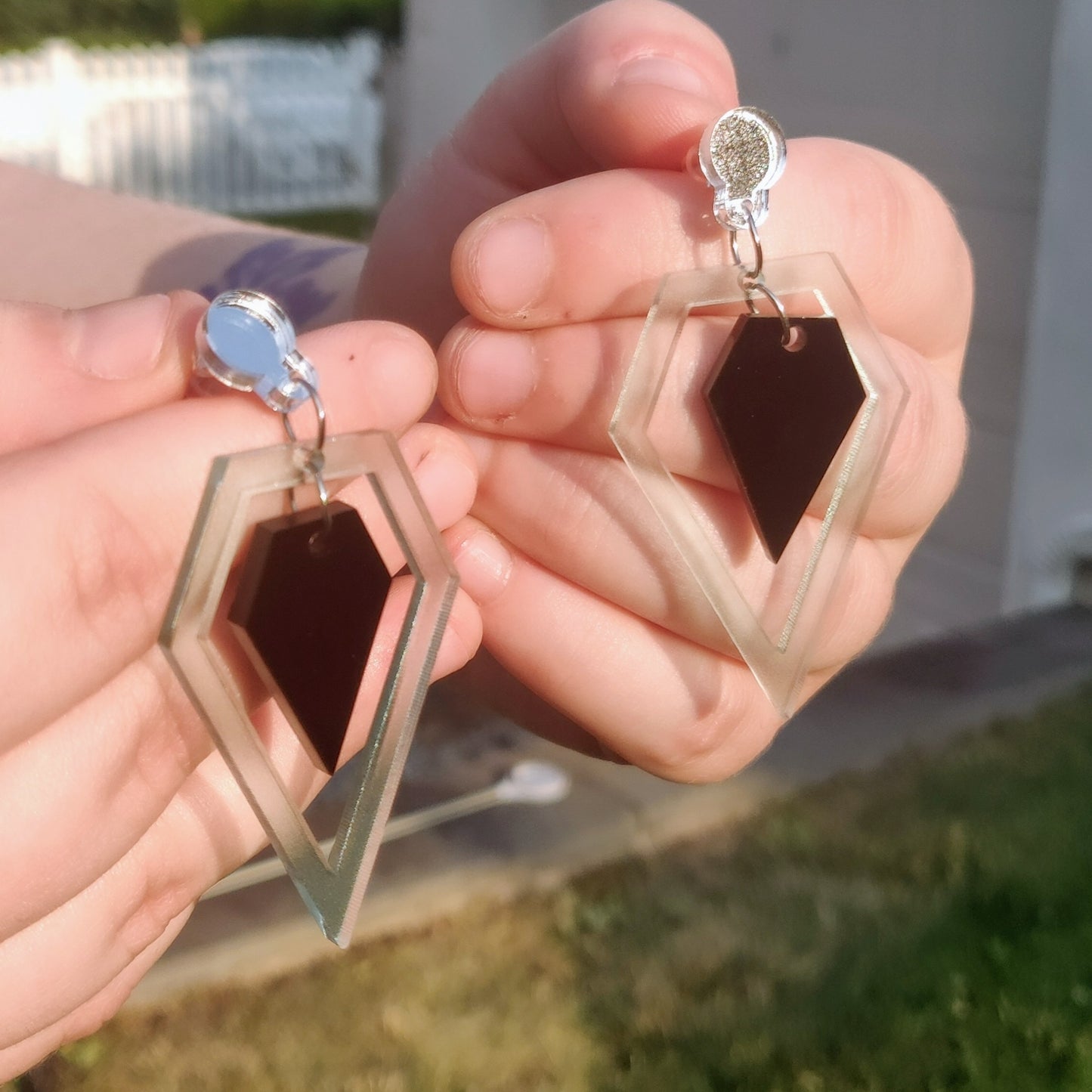 Geometric black and glass diamond shaped earrings in hand