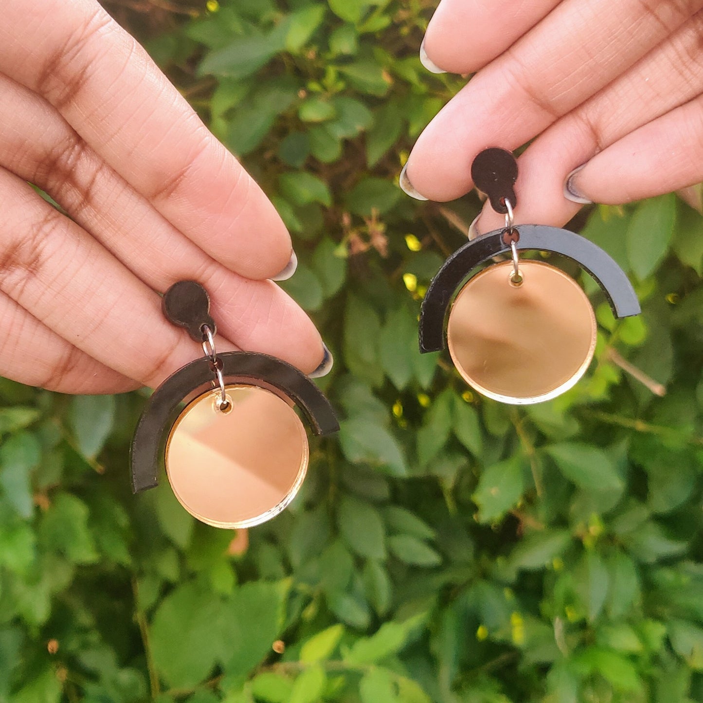 Geometric black and gold circle earrings in hand
