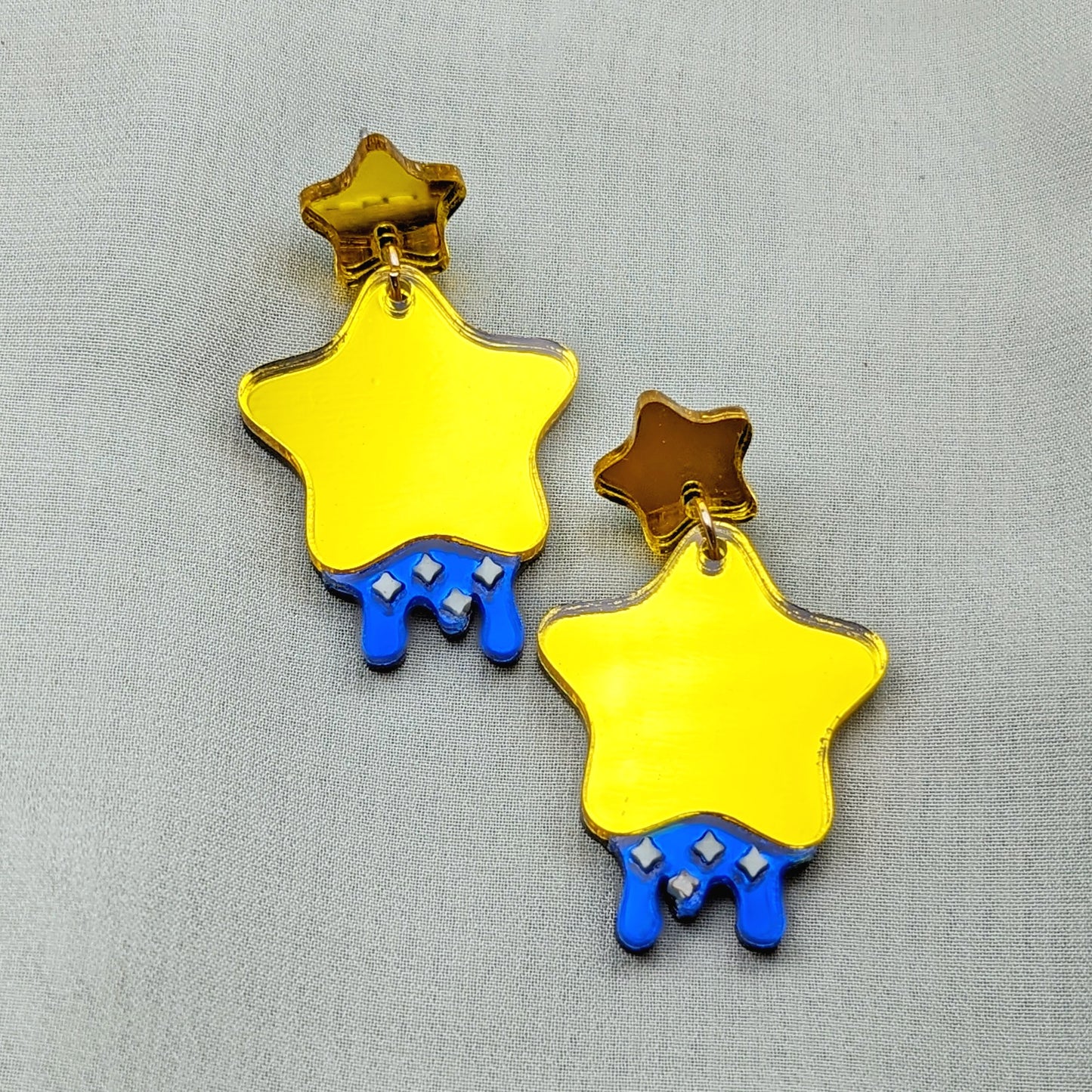 yellow star shaped dangle earrings with blue dripping below and small pastel yellow stars with yellow star stud posts.