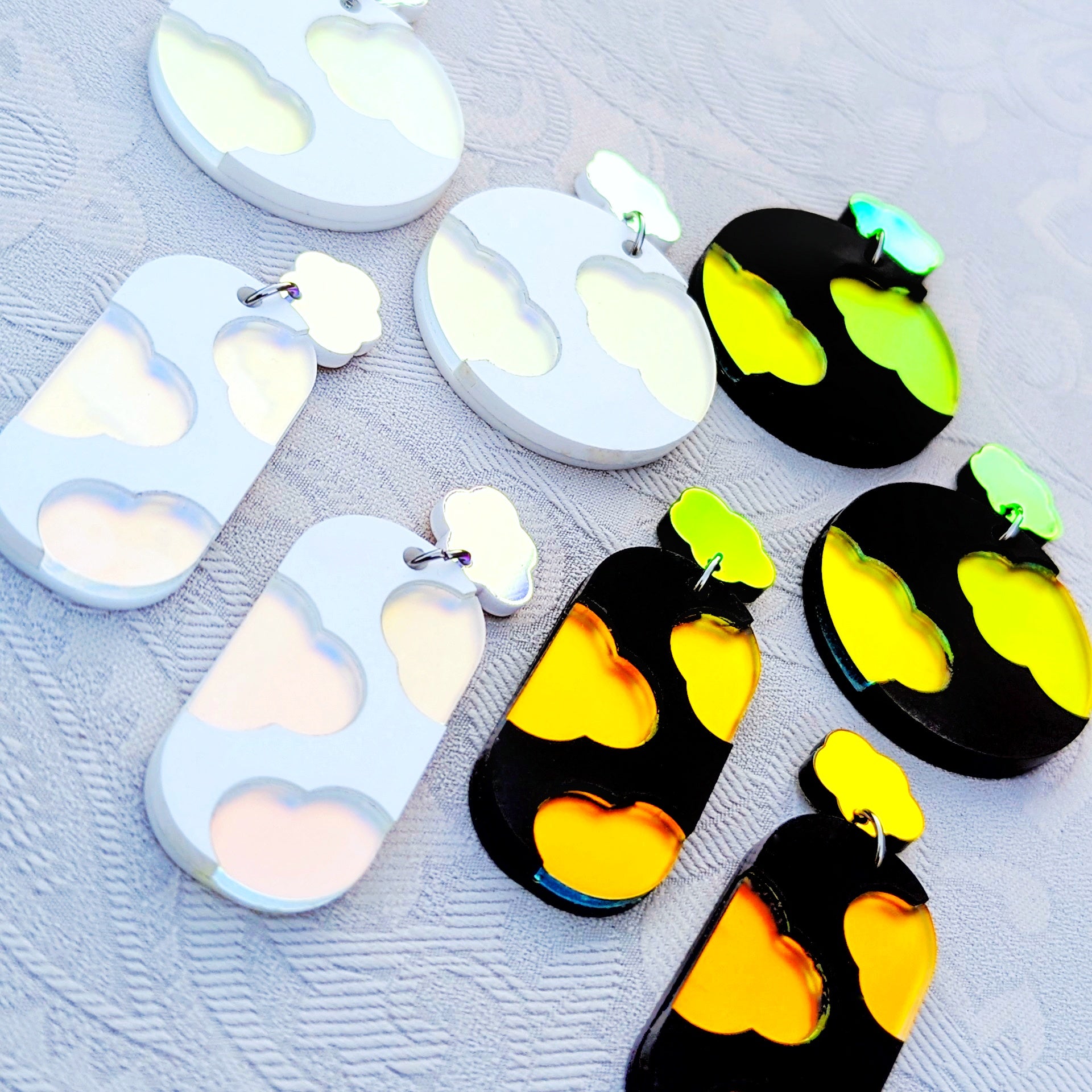 Black and white earrings with iridescent clouds in circular or oval shapes.