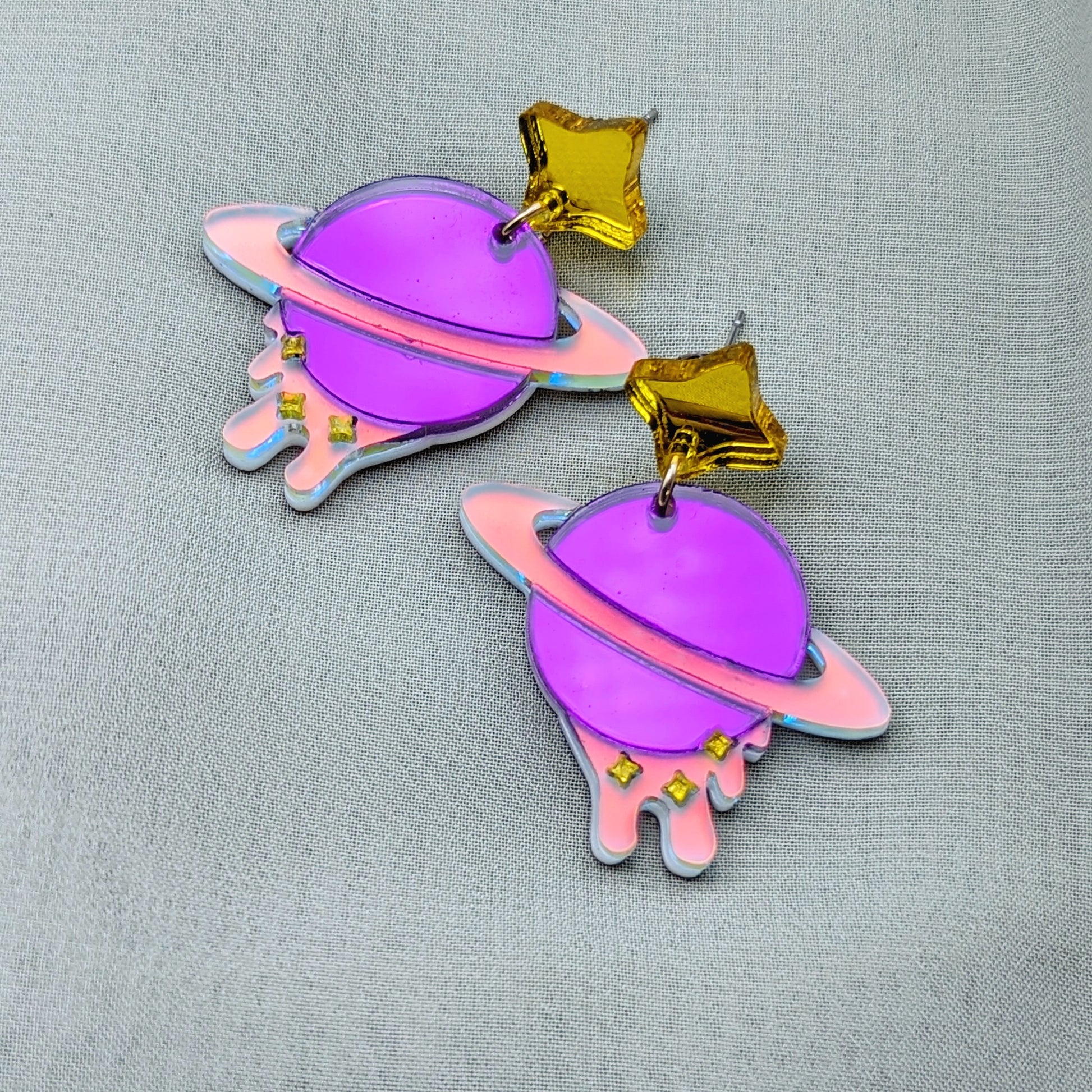 purple planet shaped dangle earrings with matte iridescent planetary rings, iridescent dripping below and small yellow stars with yellow star stud posts 