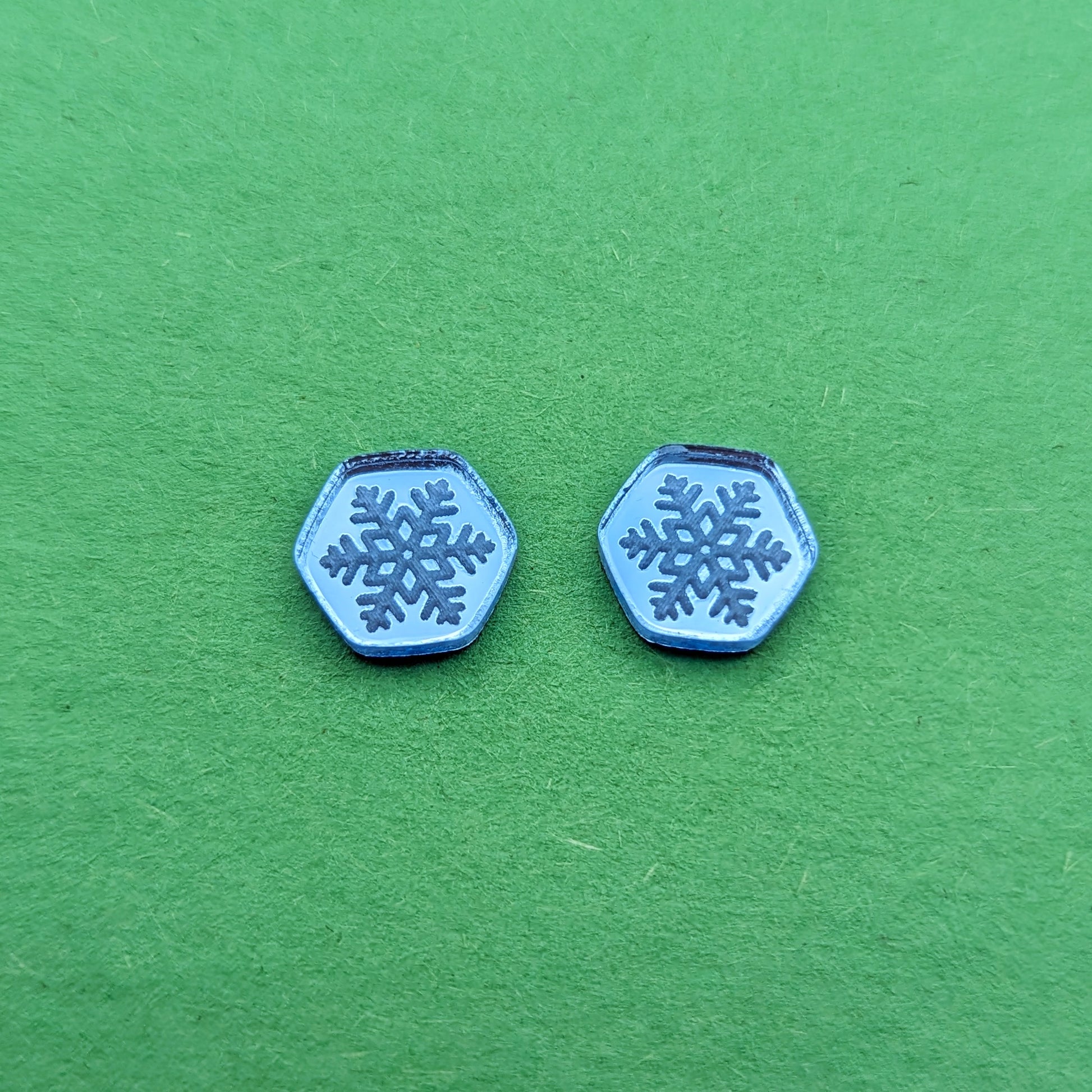 Light blue acrylic hexagon stud earrings with engraved snowflakes.