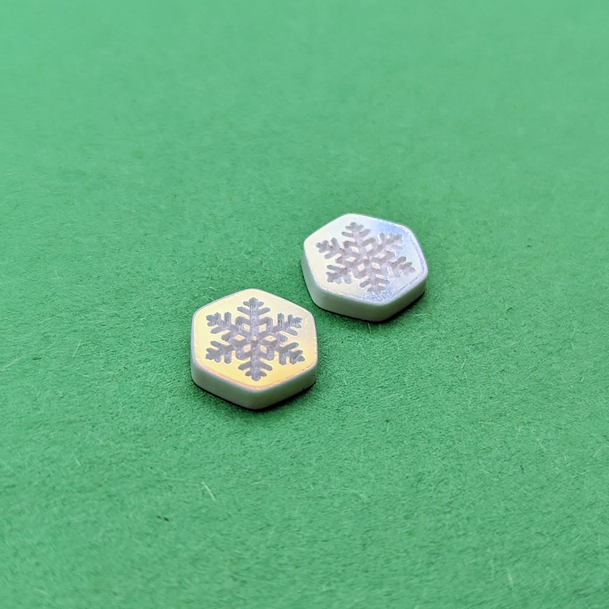 Iridescent acrylic hexagon stud earrings with engraved white snowflakes.